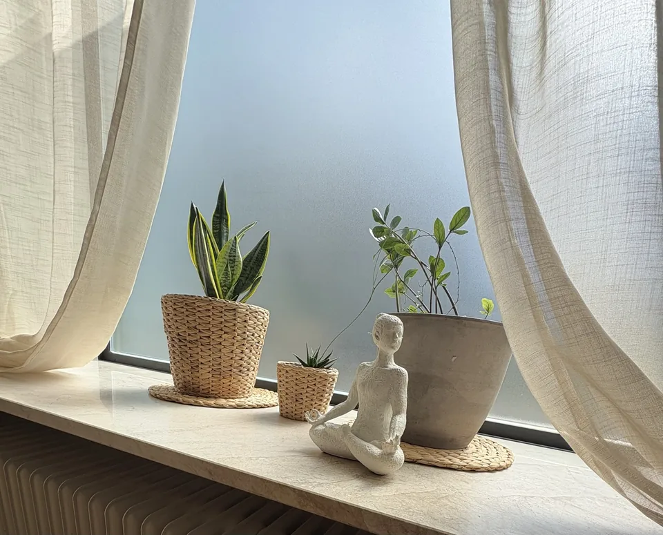 Pflanzen und Yogafigur auf der hellen Fensterbank